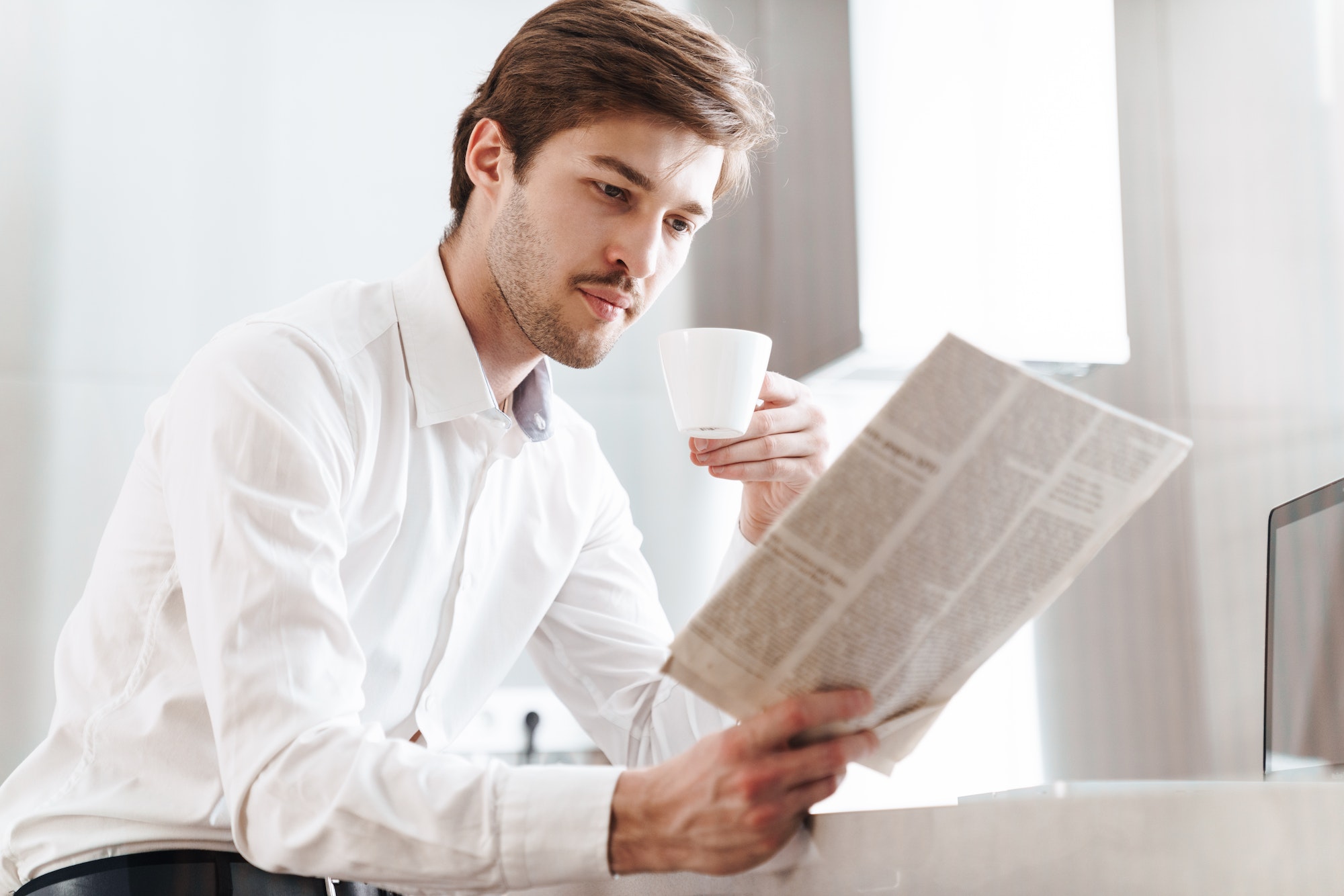 Photo of thinking businessman drinking coffee and reading newspaper